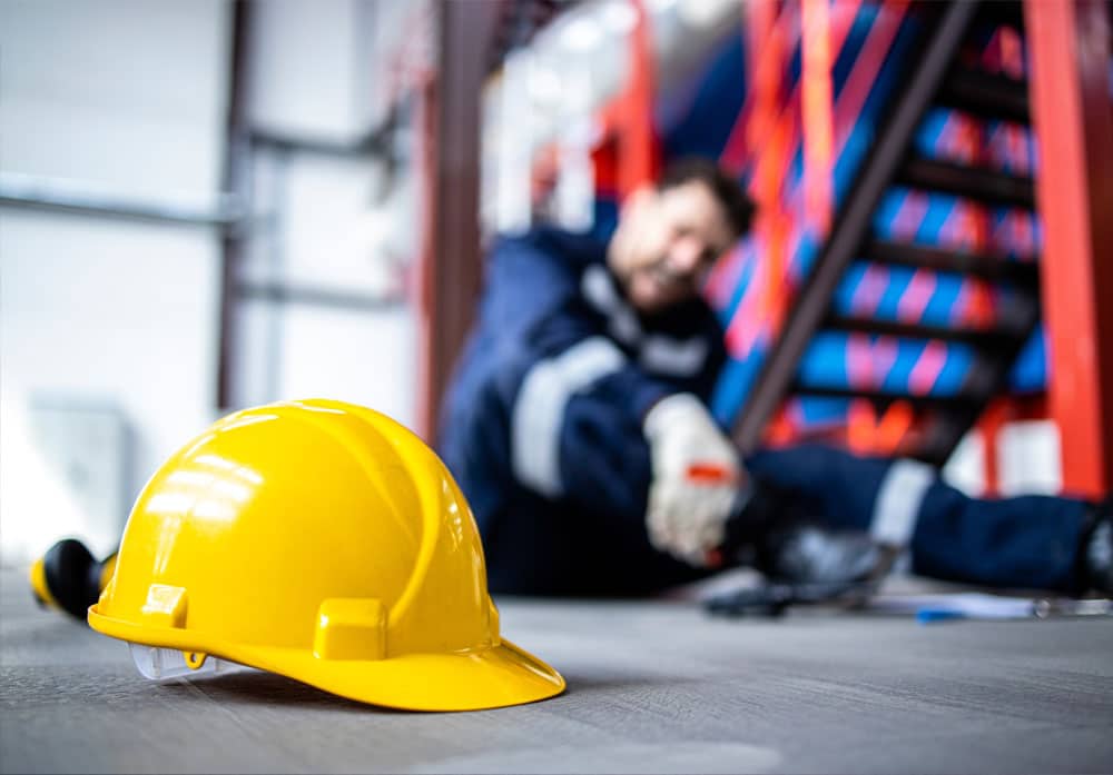 Injured worker in background with hard hat in foreground – representing workers’ compensation cases in Montana.